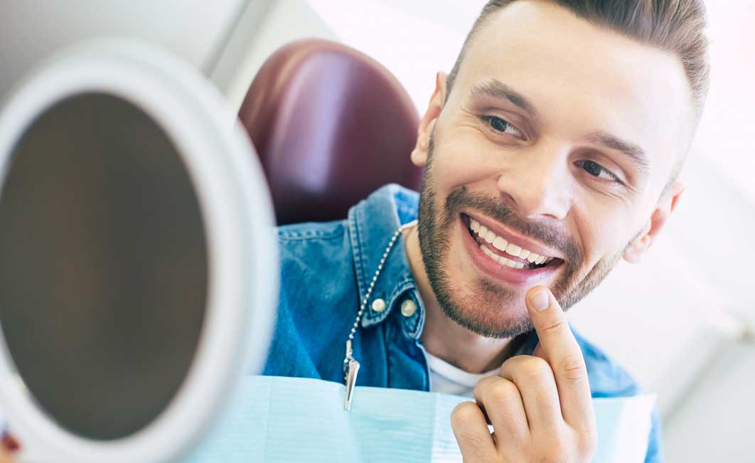 smiling in mirror with new teeth